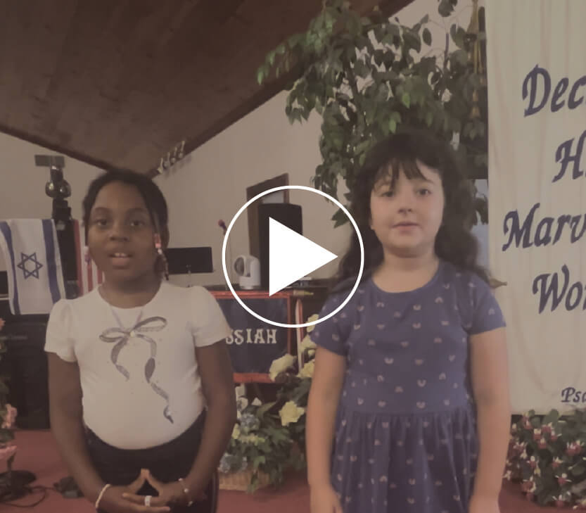 Two young girls standing in Faith Temple Church and a video play button